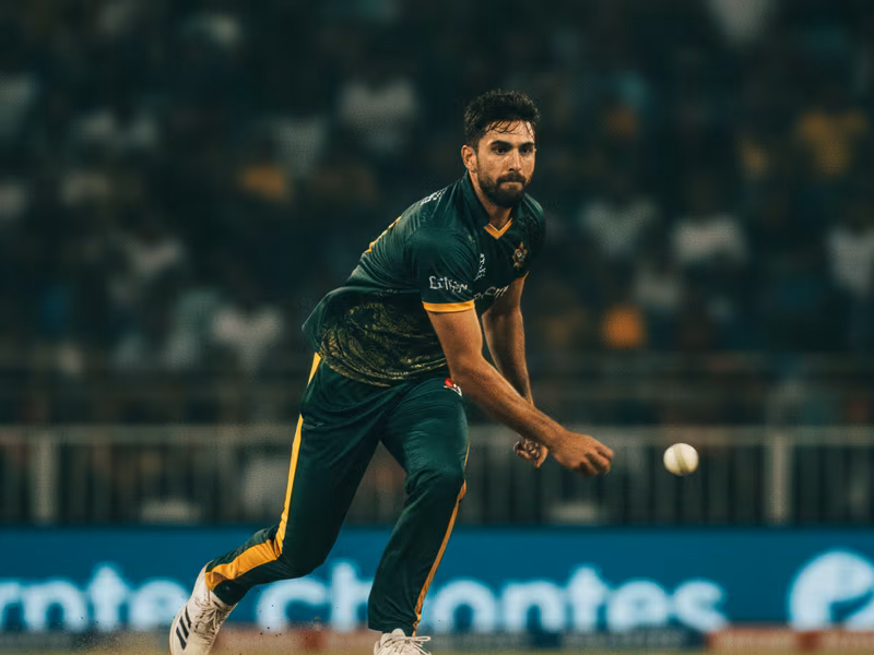 Cricket fast bowler in delivery stride under floodlights
