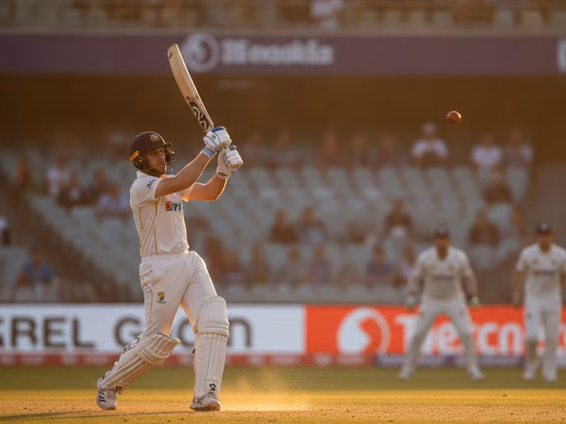 Batsman hitting a lofted drive in golden afternoon light
